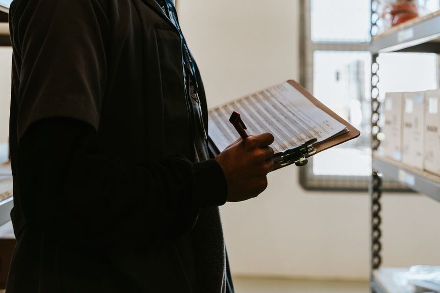 Profissional conferindo uma lista presa a uma prancheta em um depósito